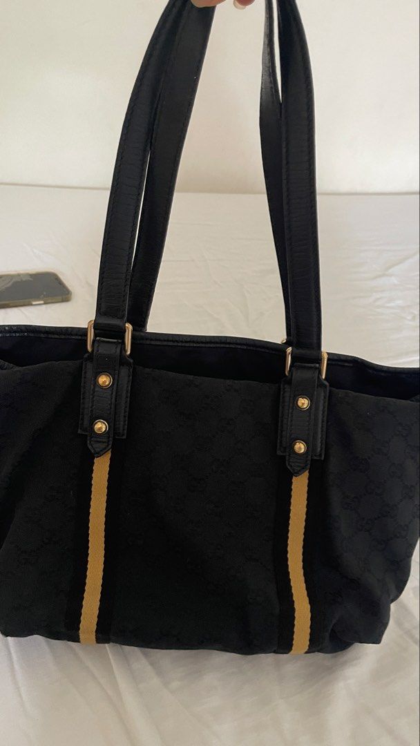 Gucci Black GG Monogram Canvas Tote Bag (Category: Luxury Bags & Wallets) located in Rizal. Submitted by annelimited_stuffs (Listing ID 1470670375, Image 1). Description: - Authentic Gucci tote bag in black GG monogram canvas - Features iconic yellow and black web stripe accents - Premium black leather double top handles and gold-tone hardware - Spacious interior compartment for everyday essentials - Condition: Minor wear on bottom corner stitchi