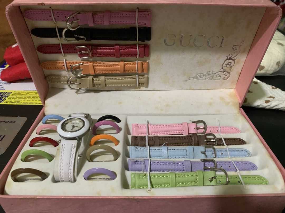 Gucci Interchangeable Bezel Watch Set with Extra Straps (Category: Women's Watches) located in Antipolo. Submitted by cebb888 (Listing ID 1470650592, Image 1). Description: - Brand: Gucci - Set Includes: 1 white bezel watch body, 10 colorful interchangeable bezel rings, and 10 leather straps - Strap Colors: Pink, black, red, orange, beige, brown, blue, purple, green, and more - Hardware: Gold-tone buckles and strap loops - Packaging: Original pin