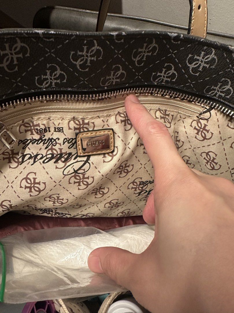 Guess Monogram Tote Bag with Charm (Category: Tote Bags) located in Manila. Submitted by anniesam (Listing ID 1470593832, Image 3). Description: - Brand: Guess authentic 100% - Design: Black and grey monogram pattern with tan adjustable straps - Hardware: Silver-tone with hanging Guess logo charm - Closure: Secure zip top - Interior: Clean beige branded fabric lining with zipped pocket and metal tag - Condition: Excellent, very clean inside and o