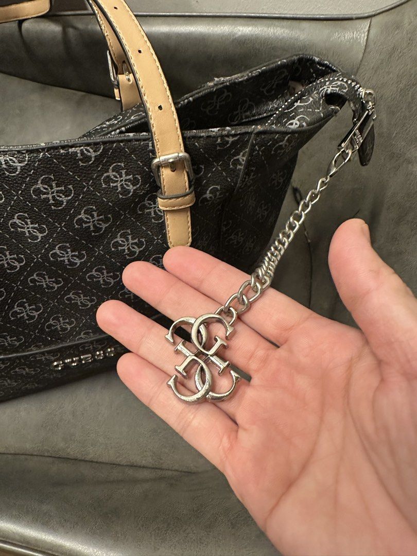 Guess Monogram Tote Bag with Charm (Category: Tote Bags) located in Manila. Submitted by anniesam (Listing ID 1470593832, Image 2). Description: - Brand: Guess authentic 100% - Design: Black and grey monogram pattern with tan adjustable straps - Hardware: Silver-tone with hanging Guess logo charm - Closure: Secure zip top - Interior: Clean beige branded fabric lining with zipped pocket and metal tag - Condition: Excellent, very clean inside and o