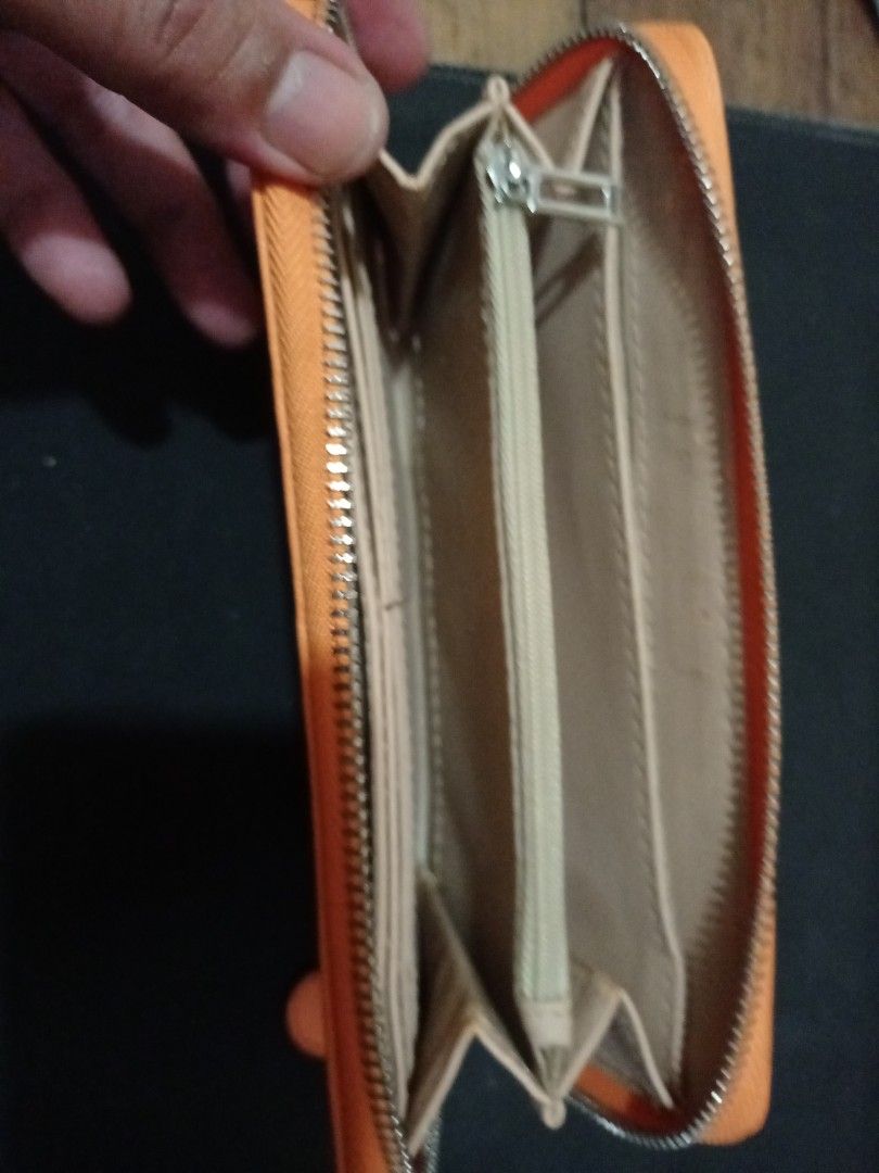 Guess Orange Zip Around Long Wallet (Category: Wallets & Card holders) located in Manila. Submitted by luckyeagle-7ff8 (Listing ID 1470589114, Image 3). Description: - Brand: Guess - Color: Bright orange with light beige interior - Closure: Smooth zip-around with matching pull tab - Exterior: Metal logo plate on the front - Interior: Multiple card slots, slip compartments, and a middle zippered coin pocket - Condition: Clean inside and out, excel