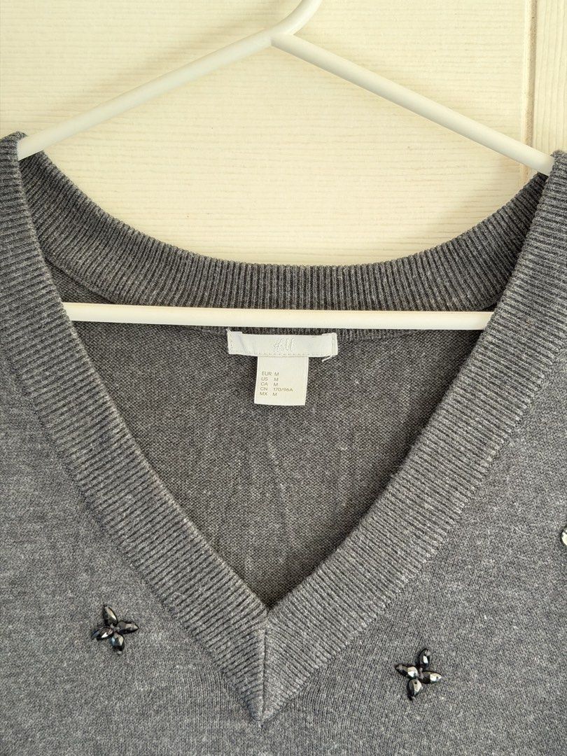 H&M Dark Gray V-Neck Sweater with Beads (Category: Coats, Jackets and Outerwear) located in Manila. Submitted by cinnmoroll (Listing ID 1470597729, Image 2). Description: - Brand: H&M - Color: Dark gray - Style: V-neck with long sleeves - Details: Scattered rhinestone and black bead embellishments on the front - Size: Medium (M) - Material: Comfortable knit fabric - Versatile: Easy to pair with jeans or skirts.