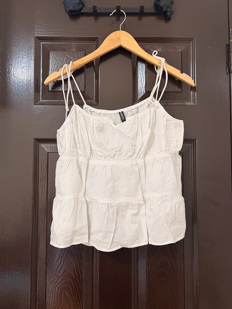 H&M Divided White Tiered Cami Top Size 8 (Category: Sleeveless) located in Marikina City. Submitted by _bananahanaa (Listing ID 1470675856, Image 1). Description: - Brand: H&M Divided - Size: US 6 / EUR 38 / CN 170/92A (fits medium-large) - Color: White - Material: Soft cotton-blend fabric - Design: V-neckline with gathered details, double spaghetti straps, and a flowy tiered silhouette - Condition: Great casual piece, easy to match with shorts o