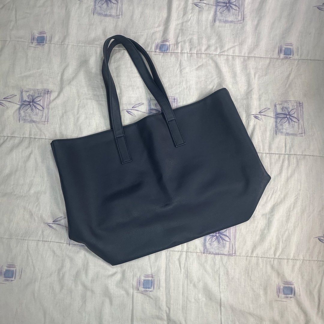 Humi - Navy Oversized Tote Bag (Category: Tote Bags) located in Muntinlupa City. Submitted by pickjes (Listing ID 1470714550, Image 3). Description: Brand: Humi Color: Navy Blue - A classic, minimalist silhouette crafted from soft, lightweight vegan leather. - Has inner pockets on one side. - Very spacious. Perfect for work to travel. Can fit laptop, tablets, planner, books, shoes, tumbler, toiletries Measurements laid flat: - Width: 18.5” - Heig