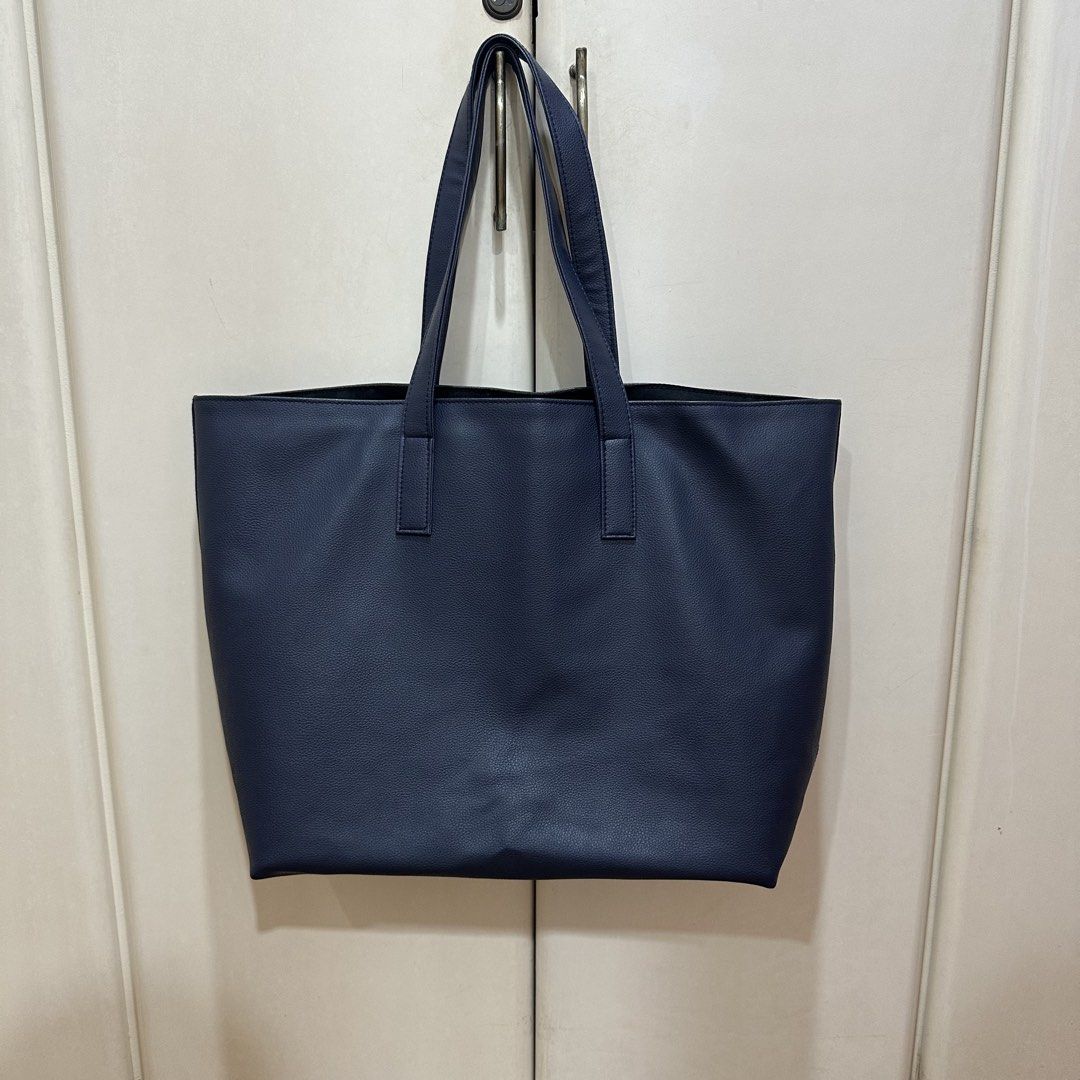 Humi - Navy Oversized Tote Bag (Category: Tote Bags) located in Muntinlupa City. Submitted by pickjes (Listing ID 1470714550, Image 2). Description: Brand: Humi Color: Navy Blue - A classic, minimalist silhouette crafted from soft, lightweight vegan leather. - Has inner pockets on one side. - Very spacious. Perfect for work to travel. Can fit laptop, tablets, planner, books, shoes, tumbler, toiletries Measurements laid flat: - Width: 18.5” - Heig