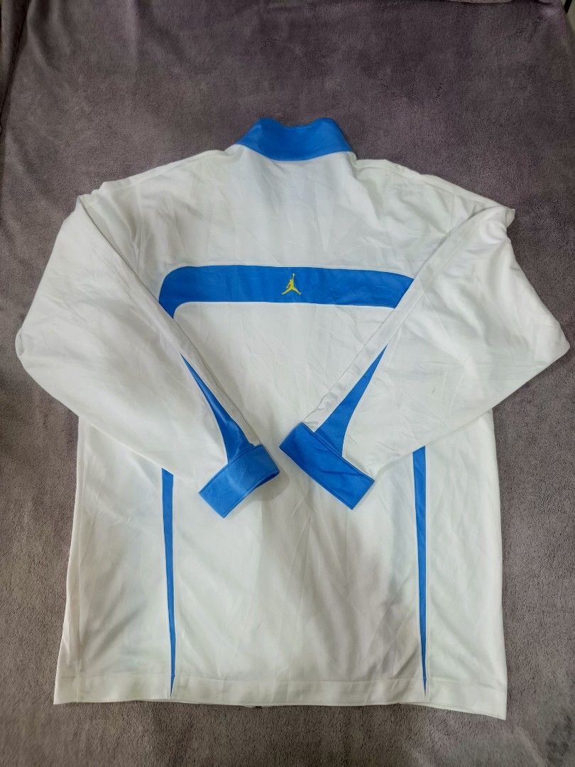 Jordan White and Blue Track Jacket (Category: Coats, Jackets and Outerwear) located in Bacolod City. Submitted by jimar4955 (Listing ID 1470742636, Image 2). Description: - Color: White with bright blue panels and collar - Branding: Small yellow Jumpman logo on chest and back yoke - Closure: Full zip up to mock neck - Details: Button cuffs and two front button-closure pockets - Condition: Clean fabric throughout.