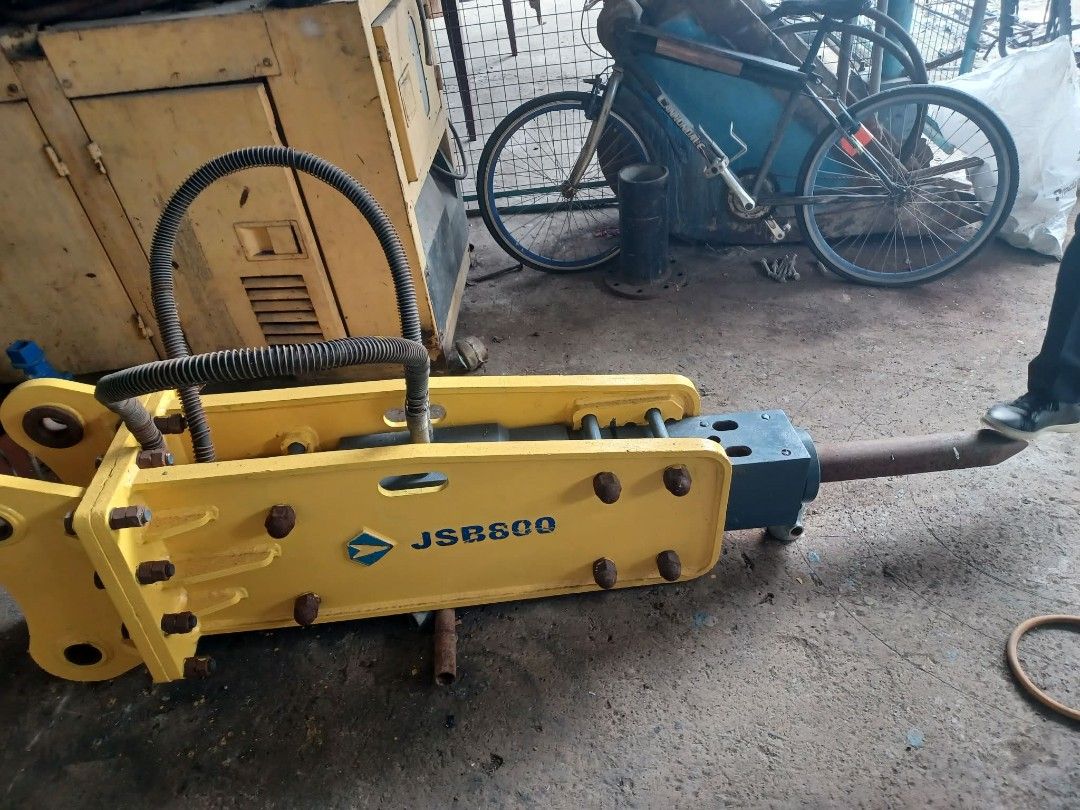 JSB800 Hydraulic Breaker Excavator Attachment (Category: Construction Tools & Equipment) located in San Mateo. Submitted by mervinvelasco (Listing ID 1470742892, Image 2). Description: - Model: JSB800 heavy-duty hydraulic breaker attachment for 1/2 size excavator - Color/Design: Yellow housing with black hydraulic lines and steel chisel bit - Condition: Sturdy industrial construction, ready for heavy site use - Application: Ideal for tough excava
