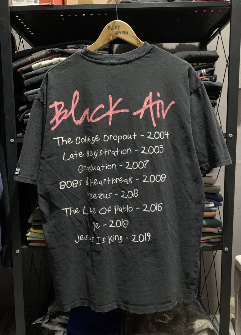 Kanye West Discography T-Shirt (Category: Tshirts & Polo Shirts ) located in Manila. Submitted by consencino97571 (Listing ID 1470713656, Image 2). Description: - Design: Black Air graphic tee with a cool vintage wash and distressed collar ribbing - Front: Kids walking graphic with 'BLACK AIR Global Spread' lettering - Back: Handwritten-style text listing Kanye West albums and release years from The College Dropout to Jesus Is King - Material: Pr