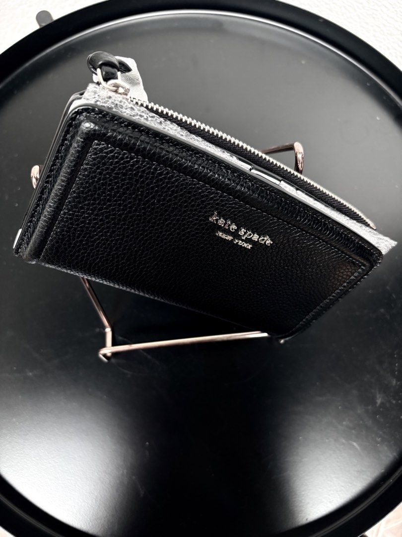 Kate Spade New York black leather wallet (Category: Wallets & Card holders) located in Quezon City. Submitted by new.cuteshop (Listing ID 1470663317, Image 2). Description: - Brand: Kate Spade - Material: Premium black pebbled leather - Hardware: Silver stamped lettering with protective wrapping still attached - Closure: Secure zip-around design - Fit: Compact and easy to slip into any daily bag - Condition: Pristine with clean stitching througho