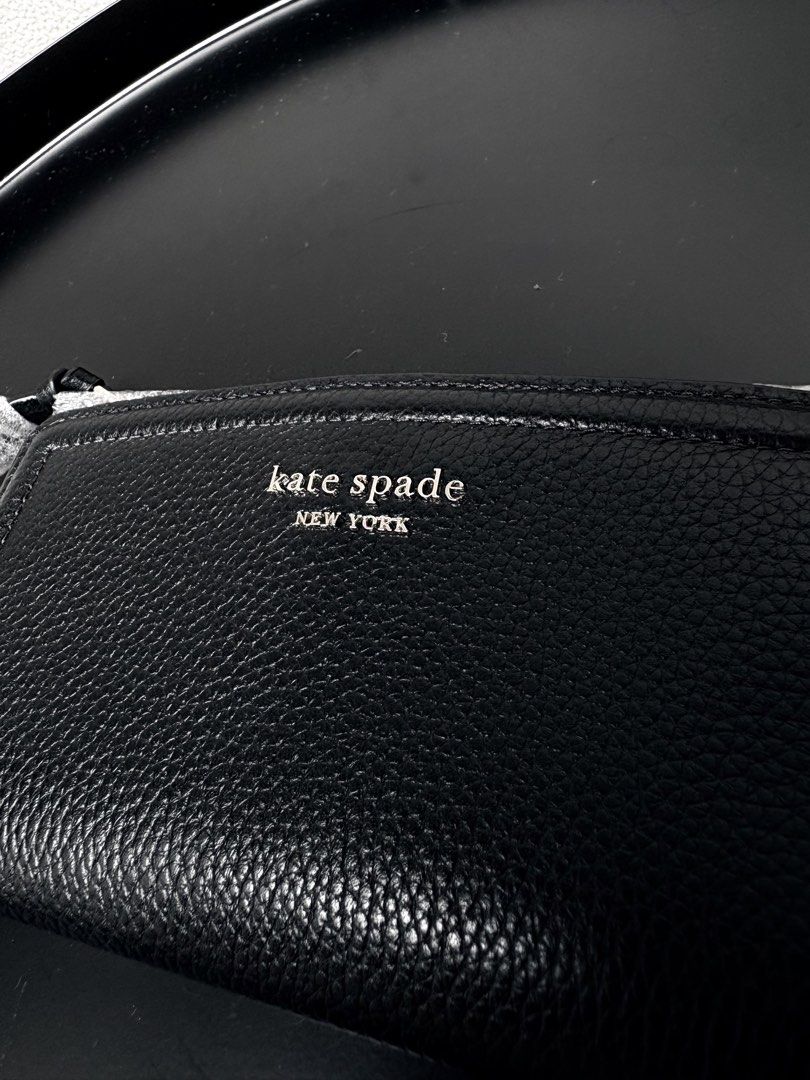 Kate Spade New York black leather wallet (Category: Wallets & Card holders) located in Quezon City. Submitted by new.cuteshop (Listing ID 1470663317, Image 3). Description: - Brand: Kate Spade - Material: Premium black pebbled leather - Hardware: Silver stamped lettering with protective wrapping still attached - Closure: Secure zip-around design - Fit: Compact and easy to slip into any daily bag - Condition: Pristine with clean stitching througho