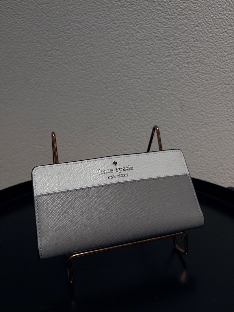 Kate Spade New York Two-Tone Wallet (Category: Wallets & Card holders) located in Quezon City. Submitted by new.cuteshop (Listing ID 1470663065, Image 2). Description: - Authentic Kate Spade New York long wallet - Color: White and grey - Material: Durable, scratch-resistant Saffiano leather - Hardware: Silver-tone front lettering - Exterior: Handy zip pocket on the back for coins - Closure: Secure snap closure - Interior: Clean and well-organized