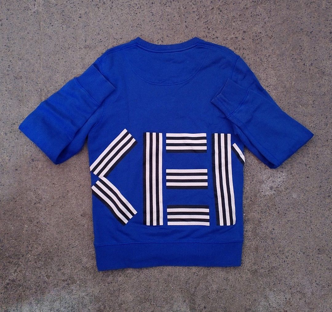 Kenzo Paris Blue Sweatshirt Size S (Category: Coats, Jackets and Outerwear) located in Pandi. Submitted by rozz_finds (Listing ID 1470695958, Image 2). Description: - Brand: Kenzo Paris - Style: Blue long sleeve sweatshirt with bold white and black graphic prints on front and back - Size: LENGTH:26 / WIDTH:19 / SLEEVES:26 - Material: 100% cotton, made in Portugal - Condition: Brand new with tags - Care: Machine washable (turn inside out for best 