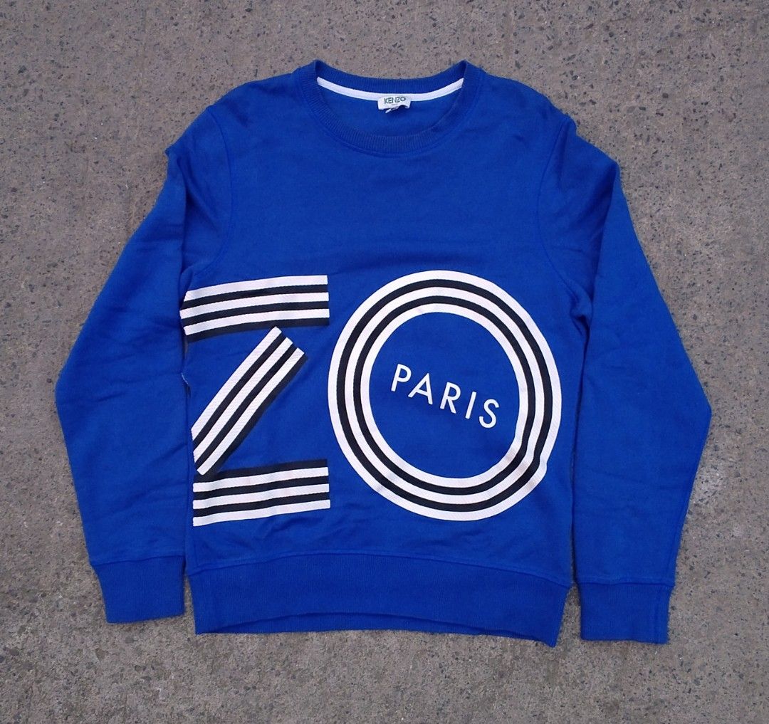 Kenzo Paris Blue Sweatshirt Size S (Category: Coats, Jackets and Outerwear) located in Pandi. Submitted by rozz_finds (Listing ID 1470695958, Image 1). Description: - Brand: Kenzo Paris - Style: Blue long sleeve sweatshirt with bold white and black graphic prints on front and back - Size: LENGTH:26 / WIDTH:19 / SLEEVES:26 - Material: 100% cotton, made in Portugal - Condition: Brand new with tags - Care: Machine washable (turn inside out for best 