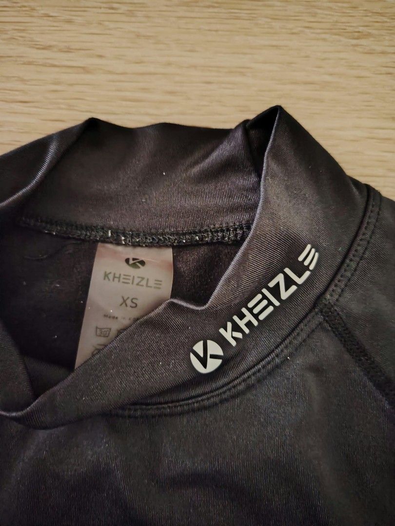 Kheizle Black Long Sleeve Compression Top Size XS (Category: Activewear) located in Nasipit. Submitted by edwingonzales498-69377 (Listing ID 1470613398, Image 3). Description: - Brand: Kheizle - Item: Black long sleeve compression top - Size: XS (Dimensions approx: 14" width x 21" length) - Details: Mock neck with white logo on collar and lower front, stretchable fabric, name label patch near bottom hem - Origin: Made in Korea - Condition/Use: Gr