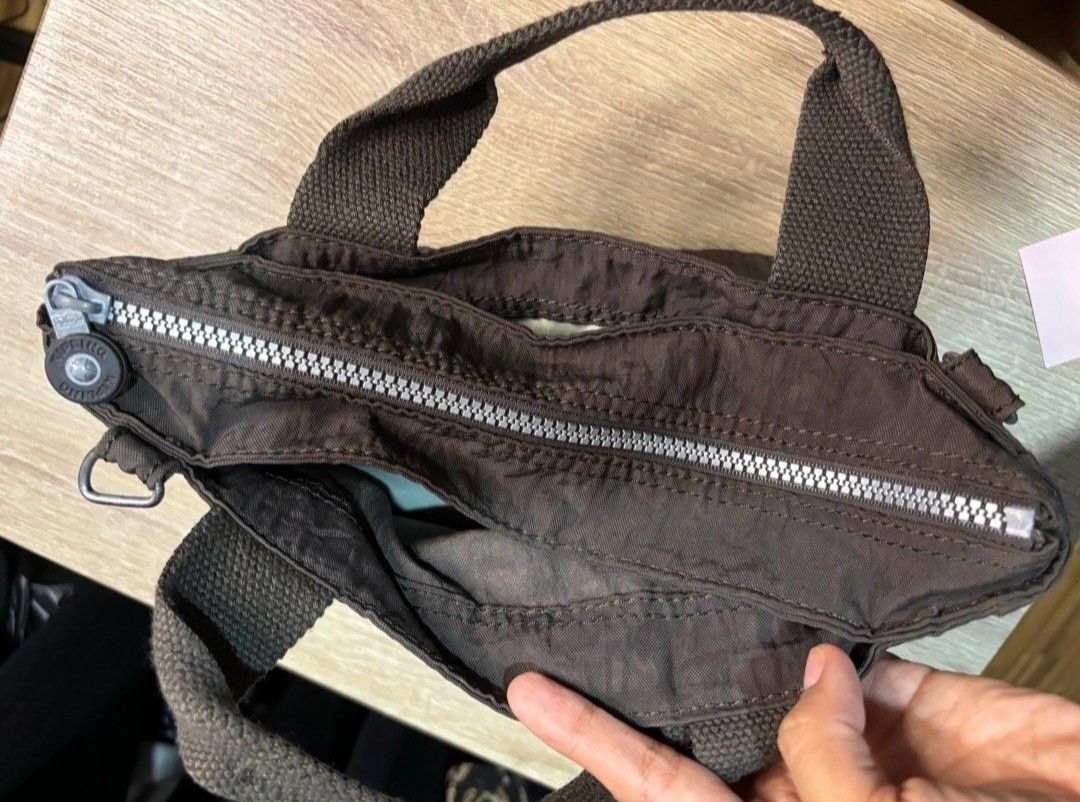 Kipling Brown Nylon Tote Bag With Shoulder Strap (Category: Tote Bags) located in Villasis. Submitted by jinkyreyann (Listing ID 1470616865, Image 2). Description: - Brand: Kipling - Material: Lightweight crinkled nylon in classic brown - Hardware: Silver-tone throughout - Straps: Dual top handles + detachable matching shoulder strap - Pockets: Main zippered compartment, interior zip pocket, and front open slip pocket with iconic round Kipling lo