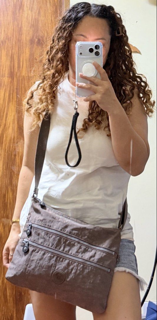 Kipling K13335-757 Crossbody Bag Brown (Category: Cross-body Bags) located in Paete. Submitted by skydruemadison (Listing ID 1470682735, Image 2). Description: - Brand: Kipling Crossbody Bag - Model Code: K13335-757 - Color: Brown in signature crinkle nylon - Hardware: Silver-tone with round Kipling logo badge - Compartments: Multiple zipped front compartments for easy organization - Strap: Adjustable canvas strap for comfortable wear - Interior: