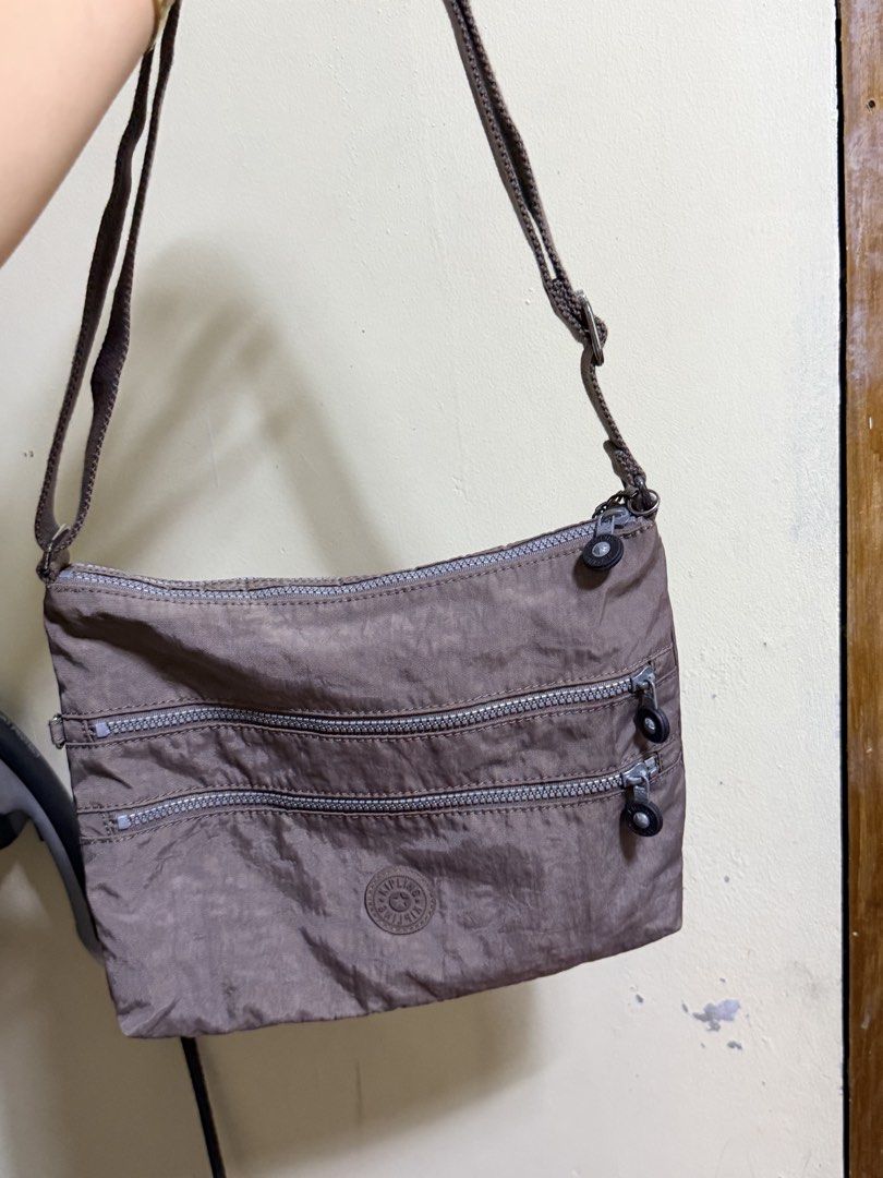 Kipling K13335-757 Crossbody Bag Brown (Category: Cross-body Bags) located in Paete. Submitted by skydruemadison (Listing ID 1470682735, Image 1). Description: - Brand: Kipling Crossbody Bag - Model Code: K13335-757 - Color: Brown in signature crinkle nylon - Hardware: Silver-tone with round Kipling logo badge - Compartments: Multiple zipped front compartments for easy organization - Strap: Adjustable canvas strap for comfortable wear - Interior:
