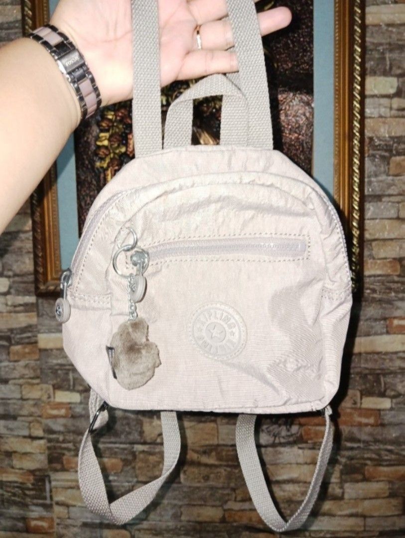 Kipling Mini Backpack Beige KPKI13860GF1 (Category: Backpacks) located in Villasis. Submitted by jinkyreyann (Listing ID 1470739609, Image 1). Description: - Authentic Kipling backpack in classic beige - Compact and lightweight design made from durable nylon crinkle fabric - Features the signature furry monkey keychain - Main compartment with inner slip pocket for organization - Handy front zipped pocket for quick-access items - Adjustable woven 