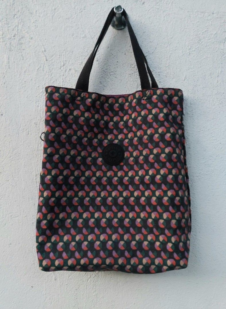 Kipling Reversible Patterned Tote Bag (Category: Tote Bags) located in Lapu Lapu. Submitted by agnesapm_29813 (Listing ID 1470673676, Image 1). Description: - Brand: Kipling - Design: Reversible 2-in-1 tote bag - Patterns: Dark geometric circle print on side A, solid purple on side B - Handles: Dual black carry handles - Details: Signature circular Kipling logo patch on both sides - Capacity: Spacious interior, perfect for daily use and errands -