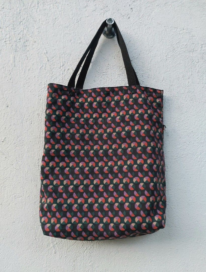Kipling Reversible Patterned Tote Bag (Category: Tote Bags) located in Lapu Lapu. Submitted by agnesapm_29813 (Listing ID 1470673676, Image 2). Description: - Brand: Kipling - Design: Reversible 2-in-1 tote bag - Patterns: Dark geometric circle print on side A, solid purple on side B - Handles: Dual black carry handles - Details: Signature circular Kipling logo patch on both sides - Capacity: Spacious interior, perfect for daily use and errands -