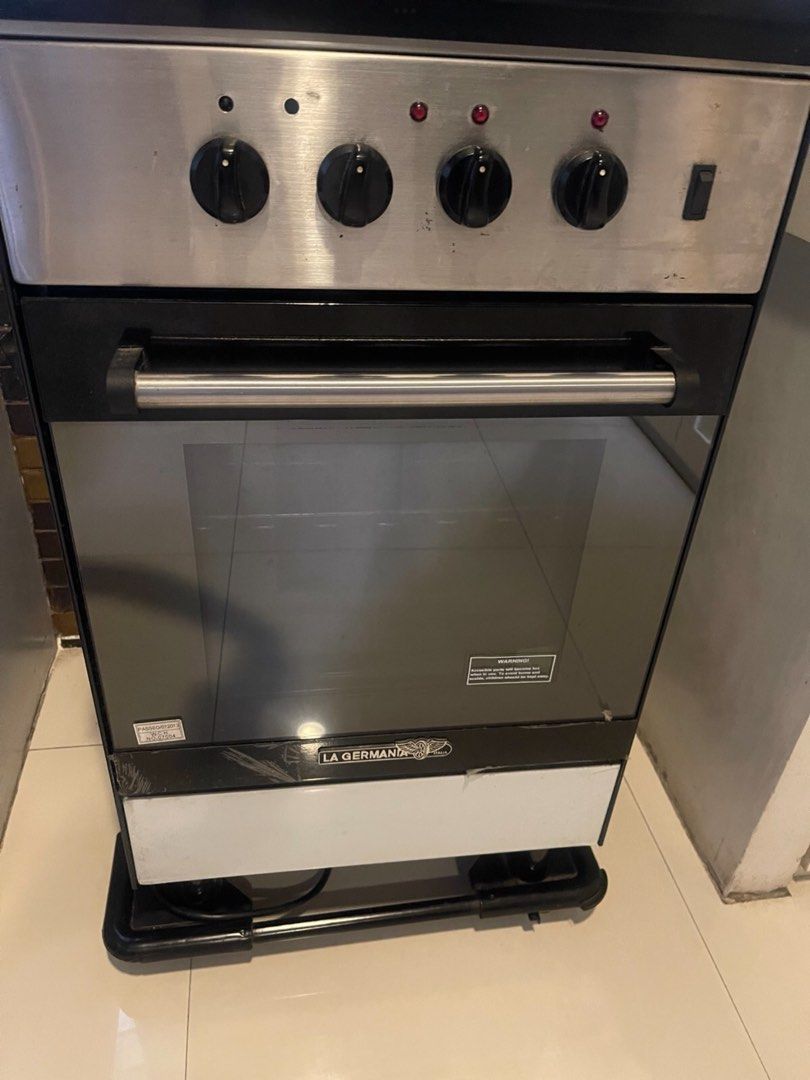 La Germania electric range (Category: Cookers) located in Manila. Submitted by roberto.enriquez (Listing ID 1470730168, Image 1). Description: - Brand: La Germania (trusted quality kitchen appliance) - Type: Gas stove and oven combo unit - Control Panel: Stainless steel with 4 black rotary knobs and push buttons - Oven: Sleek black glass door with metal handle and La Germania logo - Storage: Standard white bottom compartment drawer - Mobility: Si