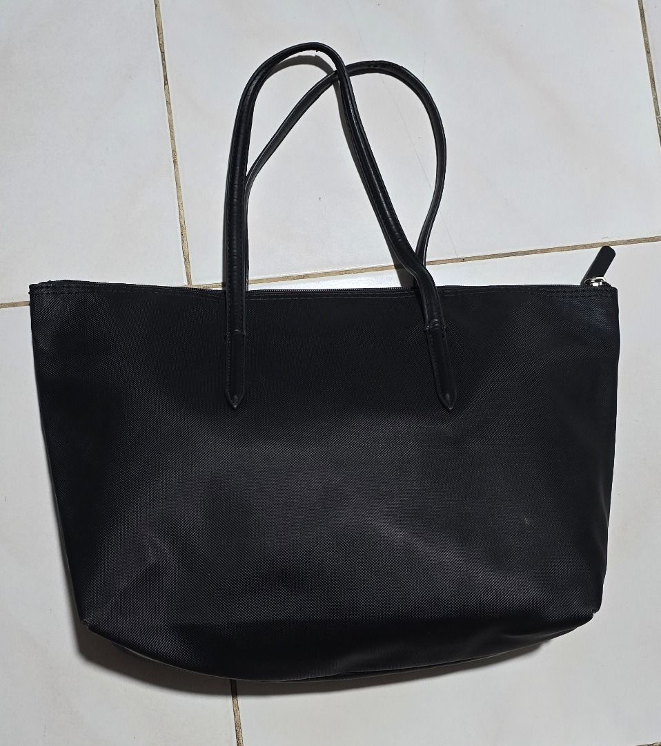 Lacoste Black Tote Bag - Negotiable!!! (Category: Tote Bags) located in Manila. Submitted by axelyuna.27 (Listing ID 1470584928, Image 2). Description: Authentic black Lacoste tote bag featuring comfortable double shoulder straps and a spacious interior with a zippered pocket. Showcases the iconic green crocodile logo on the front and inside base. Please note that the handle edges show heavy peeling and wear, but the bag is still highly functiona
