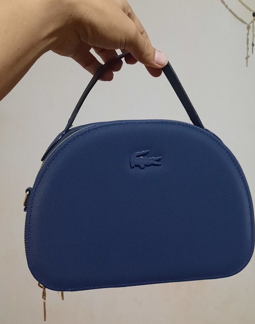Lacoste Blue Dome Crossbody Bag with Branded Strap (Category: Cross-body Bags) located in Manila. Submitted by gracjam_27 (Listing ID 1470695079, Image 3). Description: - blue Lacoste dome-shaped handbag - Stylish textured finish with elegant gold hardware - Secure double top-zipper closure - Clean dark blue interior lining - Includes a matching adjustable blue strap with bold white Lacoste branding - Versatile design: wear by the top handle or a