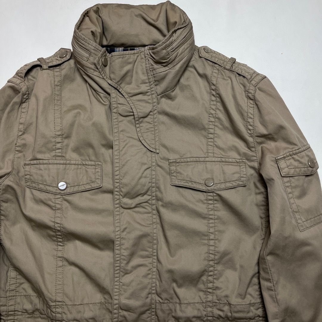 Lacoste Khaki Utility Jacket with Plaid Lining Size 45 (Category: Coats, Jackets and Outerwear) located in Caloocan City. Submitted by achilles_grails (Listing ID 1470575051, Image 3). Description: - Brand: Lacoste - Color: Khaki with navy blue, white, and yellow plaid lining - Material: 100% Cotton shell - Closure: Button and zip front with high collar and strap details - Pockets: Functional multi-pocket design on front and sleeve - Fit: Adjusta