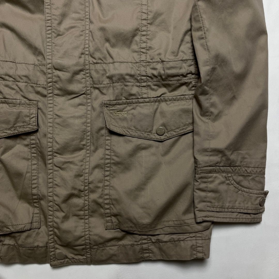 Lacoste Khaki Utility Jacket with Plaid Lining Size 45 (Category: Coats, Jackets and Outerwear) located in Caloocan City. Submitted by achilles_grails (Listing ID 1470575051, Image 2). Description: - Brand: Lacoste - Color: Khaki with navy blue, white, and yellow plaid lining - Material: 100% Cotton shell - Closure: Button and zip front with high collar and strap details - Pockets: Functional multi-pocket design on front and sleeve - Fit: Adjusta