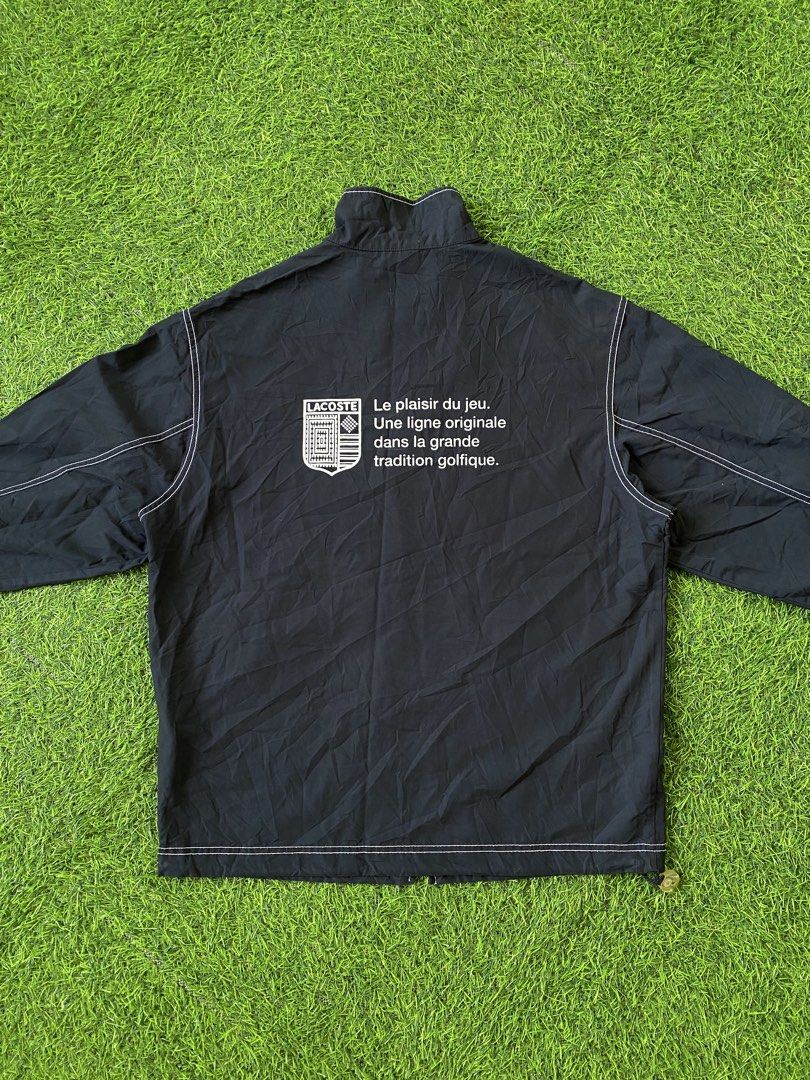 Lacoste Navy Blue Windbreaker Jacket Size 95 (Category: Coats, Jackets and Outerwear) located in Manila. Submitted by clevermountain_9c1516 (Listing ID 1470661586, Image 2). Description: - Brand: Lacoste - Color: Dark navy blue with white contrast stitching - Design details: Red, white, and navy checkered inner collar, striking white text and logo graphic on the back - Pockets: Two front pockets with secure button flaps - Fit & Comfort: Elastic c