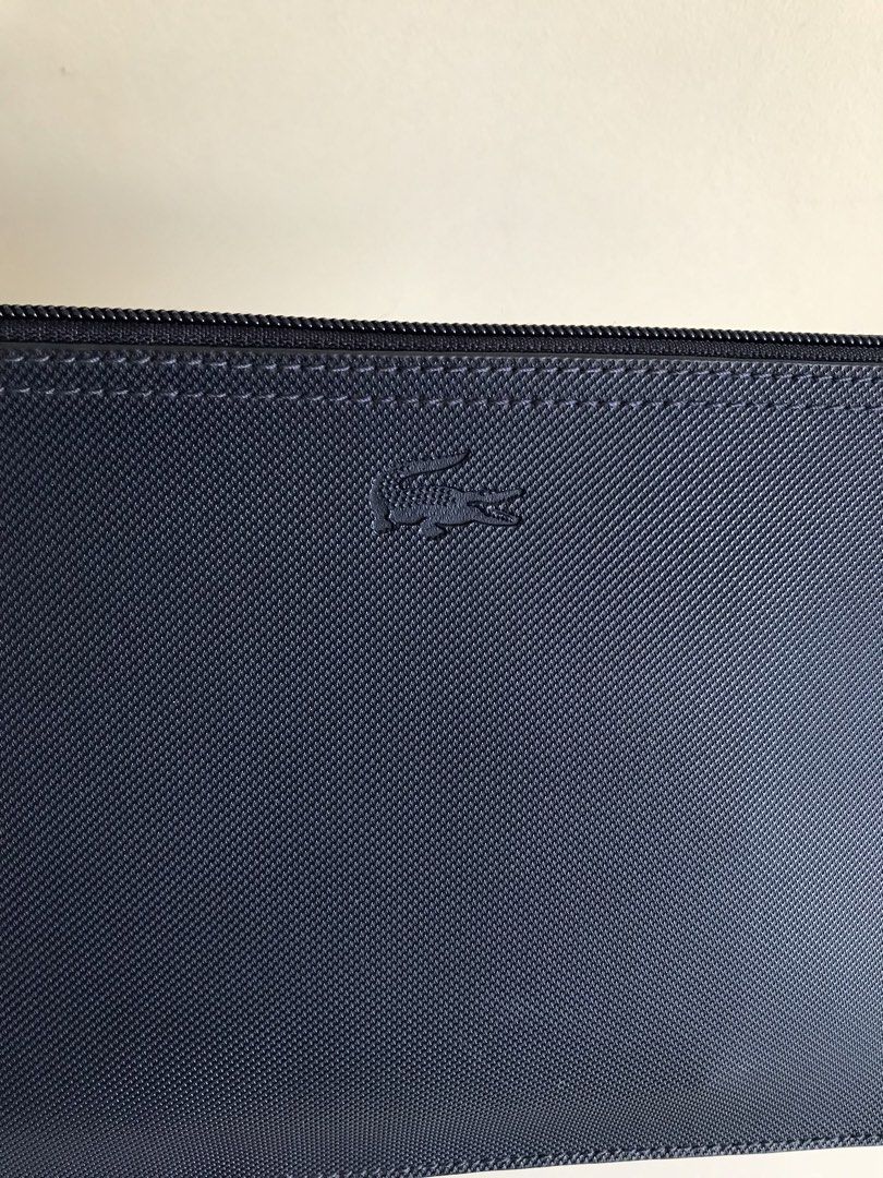 Lacoste Navy Blue Zip Pouch with Red Interior (Category: Purses & Pouches) located in Cainta. Submitted by ukaymama (Listing ID 1470608030, Image 1). Description: - Brand: Lacoste - Color: Navy blue exterior with a bright red inner lining - Material: Textured exterior and pebbled leather interior - Design: Features a debossed crocodile logo and smooth zipper closure with a matching dark pull tab - Condition: Clean interior and exterior with minim