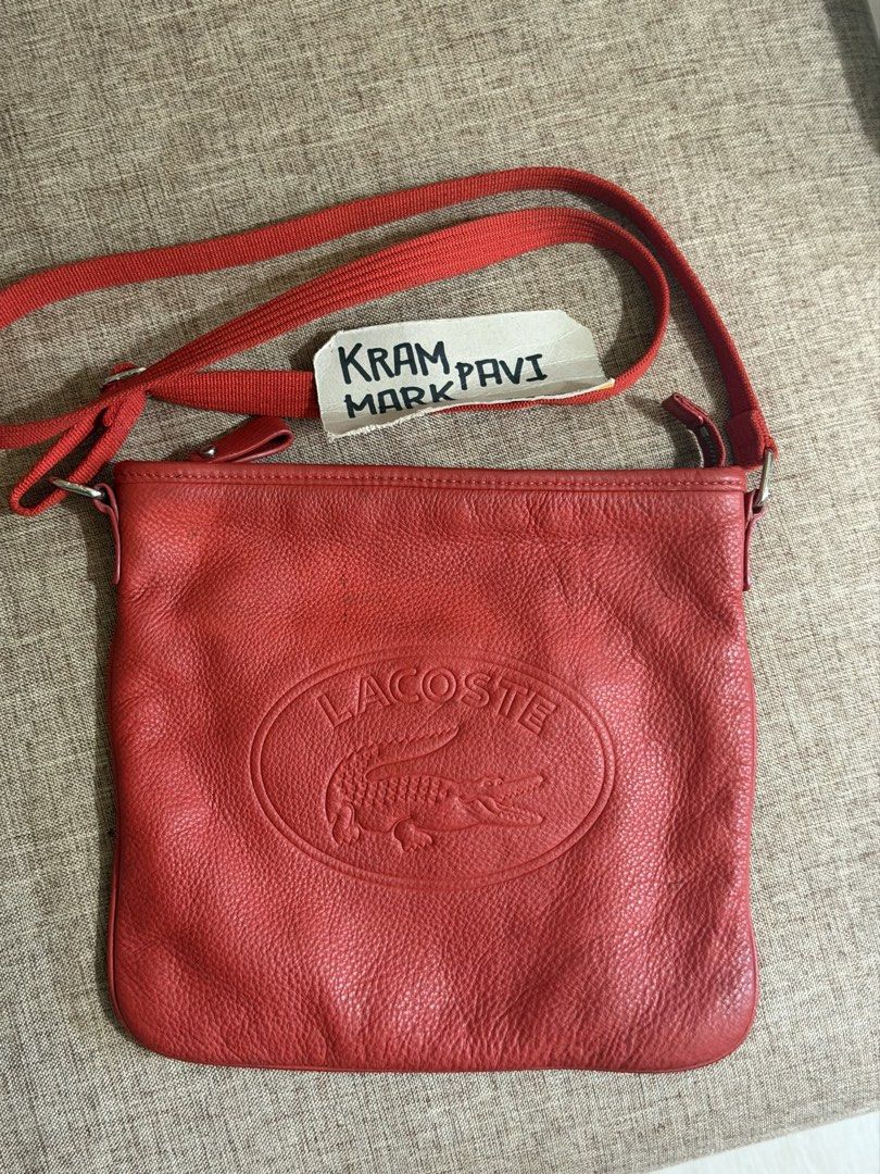 Lacoste Red Leather Crossbody Bag (Category: Cross-body Bags) located in Taguig. Submitted by markitopinas (Listing ID 1470618792, Image 1). Description: - Brand: Lacoste - Style: Red leather crossbody bag with debossed crocodile logo - Size: Medium (fits daily essentials) - Strap: Adjustable red canvas strap - Closure & Interior: Zip top closure, dark fabric lining, interior zippered pocket, and leather brand tag - Condition: Minor creasing on t