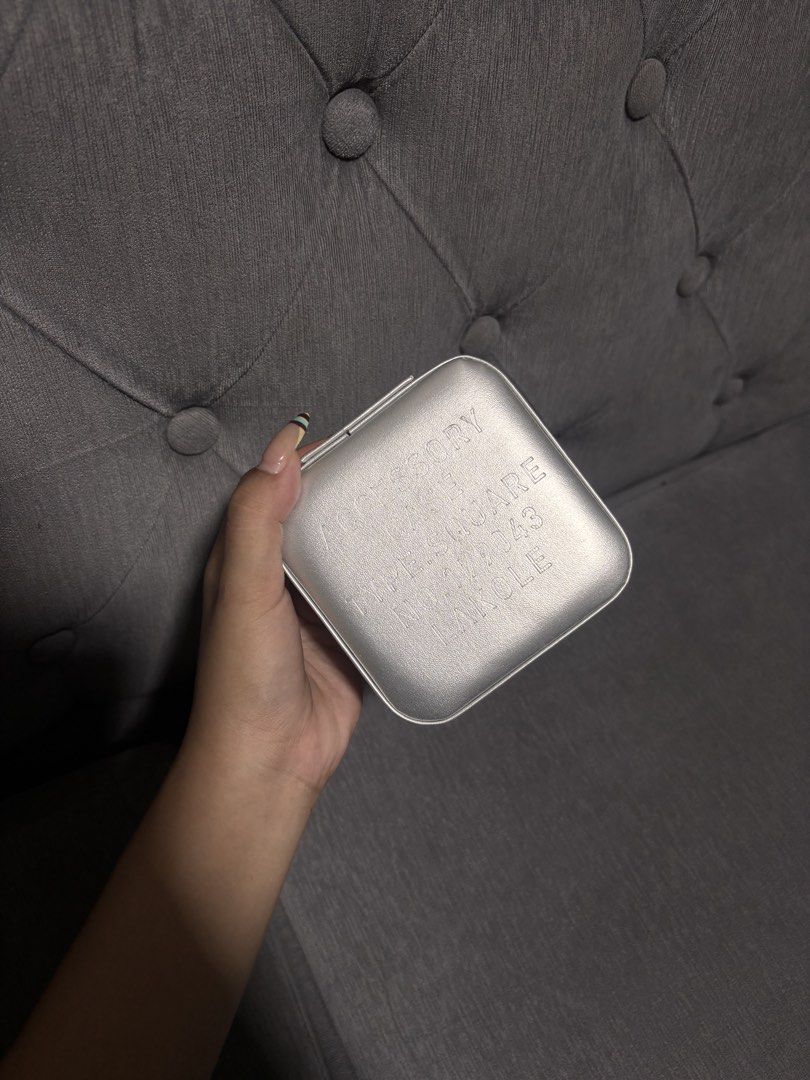Lakole Square Accessory Case Jewelry Box Silver (Category: Accessory Holder, Box & Organizers) located in Manila. Submitted by alyanarein (Listing ID 1470716005, Image 2). Description: Silver compact jewelry case by Lakole. Square shape with debossed text on the lid. Inside has ring rolls, small compartments, and hooks for necklaces under the lid. Zip-around closure keeps everything secure. Handy for travel or everyday organization..