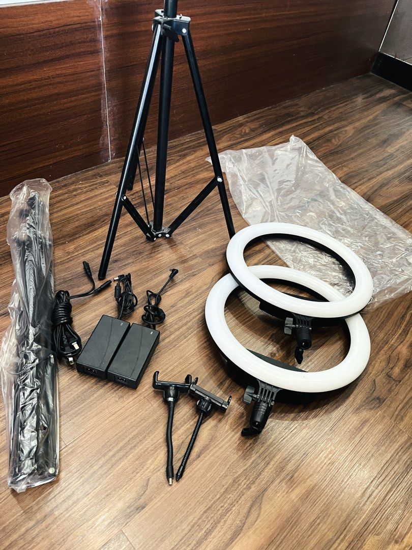 LED Ring Light with Tripod Stand and Phone Holder (Category: Lighting & Studio Equipment) located in Quezon City. Submitted by ccgem (Listing ID 1470638512, Image 2). Description: 2 sets for only ₱800 Bought at price 1100 each LED ring light setup for streaming or recording. Includes adjustable tripod stand, two ring lights, two AC/DC power adapters, flexible phone mounts, and two gooseneck attachments. Controls on the back adjust brightness and 
