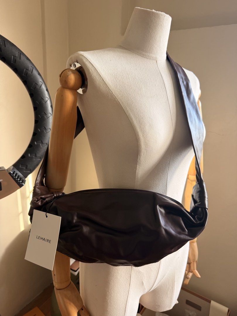 Lemaire Croissant Bag Dark Brown (Category: Luxury Bags & Wallets) located in Las Pinas. Submitted by twiceloved24 (Listing ID 1470638961, Image 1). Description: - Brand: Lemaire - Style: Croissant Shoulder Bag - Color: Dark Brown - Material: Supple lambskin leather with soft texture - Details: Signature knotted strap and top zipper closure - Interior: Fabric lining with zippered side pocket and Lemaire leather brand patch - Inclusions: Dust bag 