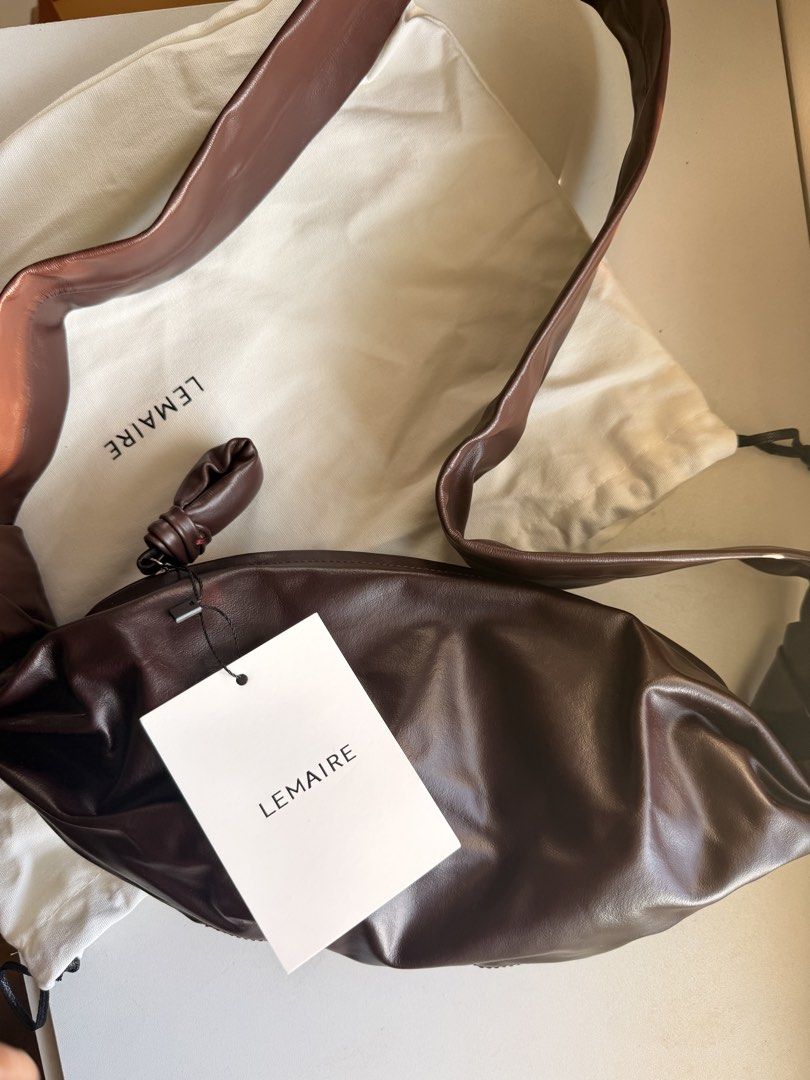 Lemaire Croissant Bag Dark Brown (Category: Luxury Bags & Wallets) located in Las Pinas. Submitted by twiceloved24 (Listing ID 1470638961, Image 2). Description: - Brand: Lemaire - Style: Croissant Shoulder Bag - Color: Dark Brown - Material: Supple lambskin leather with soft texture - Details: Signature knotted strap and top zipper closure - Interior: Fabric lining with zippered side pocket and Lemaire leather brand patch - Inclusions: Dust bag 