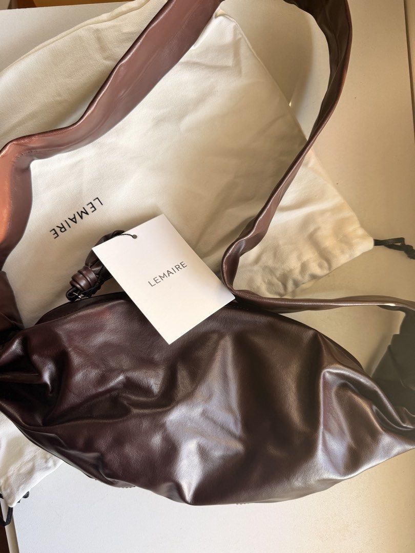 Lemaire Croissant Bag Dark Brown (Category: Luxury Bags & Wallets) located in Las Pinas. Submitted by twiceloved24 (Listing ID 1470638961, Image 3). Description: - Brand: Lemaire - Style: Croissant Shoulder Bag - Color: Dark Brown - Material: Supple lambskin leather with soft texture - Details: Signature knotted strap and top zipper closure - Interior: Fabric lining with zippered side pocket and Lemaire leather brand patch - Inclusions: Dust bag 