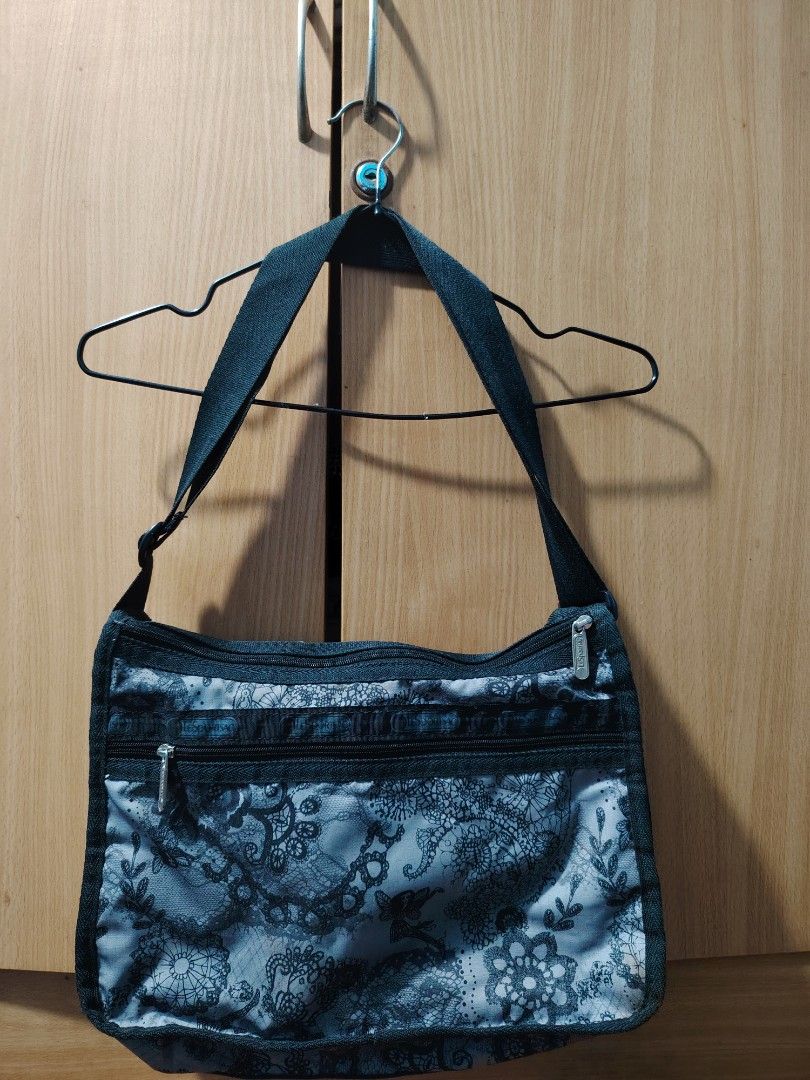 LeSportsac Black and White Lace Pattern Shoulder Bag (Category: Shoulder Bags) located in Manila. Submitted by theshopandsmile (Listing ID 1470576707, Image 1). Description: - Brand: LeSportsac - Design: Black and white lace and floral print - Material: Durable and lightweight nylon fabric - Compartments: Multiple zippered pockets on the front and main body - Strap: Adjustable black strap for custom comfort - Details: Branded zippers and signatur