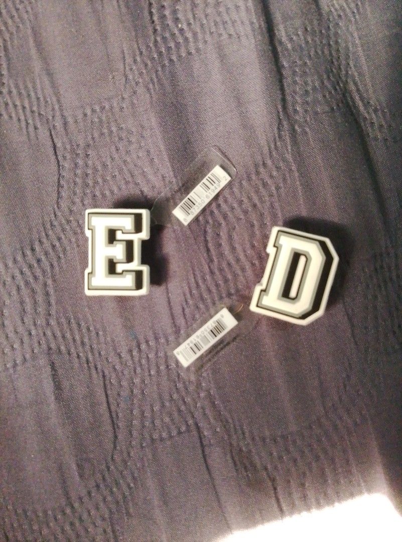 Letters E and D Jibbitz charms (Category: Charms) located in Manila. Submitted by warmfire.3fd685 (Listing ID 1470628106, Image 1). Description: - Set of 2 varsity letter charms: E and D - Stylish white and black design with grey borders - Brand new, unused condition with original barcodes on the back - Perfect for customizing clogs and footwear.