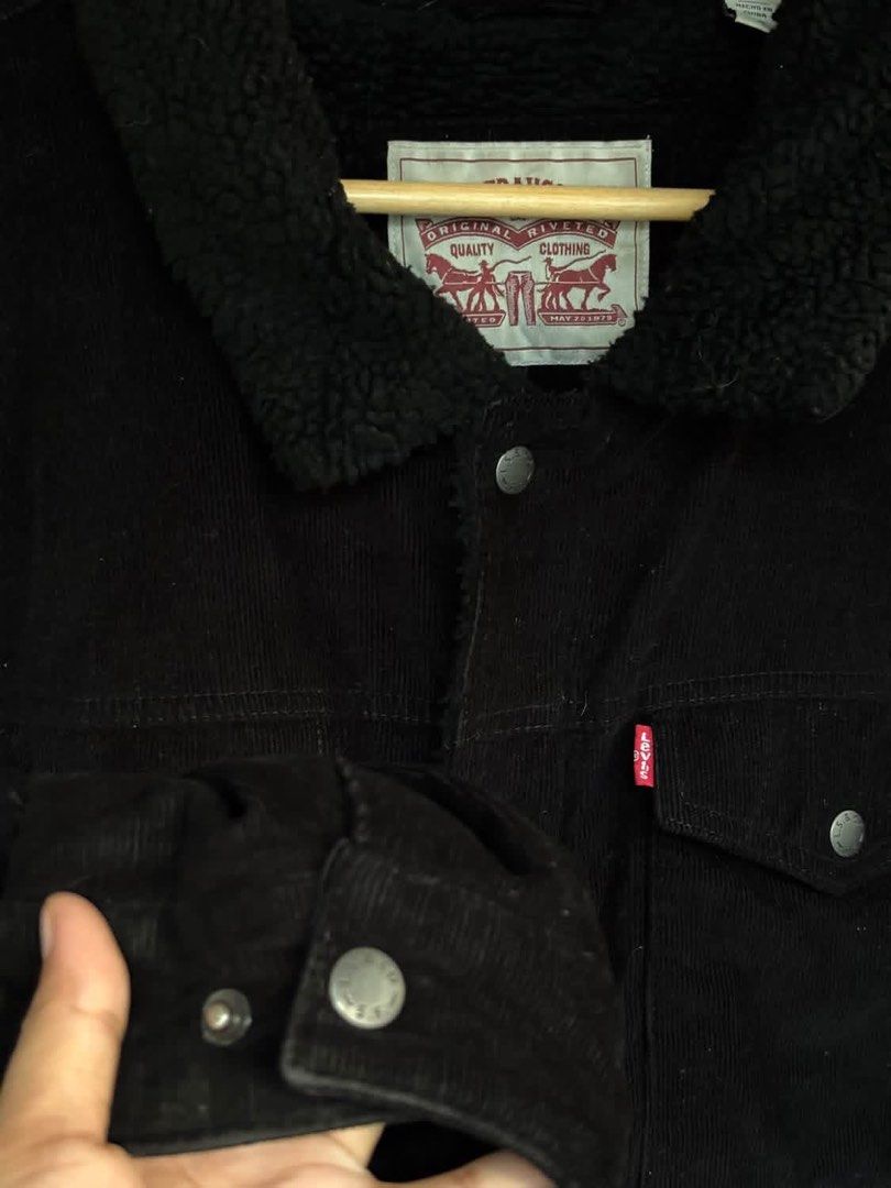 Levi's Black Corduroy Sherpa Jacket (Category: Coats, Jackets and Outerwear) located in Mati. Submitted by abu_razmey (Listing ID 1470728427, Image 3). Description: - Brand: Levi's - Material: Black corduroy with thick sherpa lining and collar - Closure: Front metal buttons plus zipper - Pockets: Two buttoned chest flap pockets and lower side pockets - Details: Iconic red Levi's tab and branded metal hardware - Fit/Use: Warm winter layer, stylish