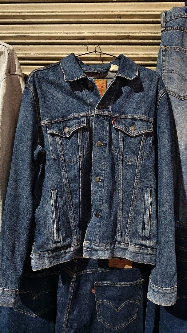 Levi's Denim Trucker Jacket Size M (Category: Coats, Jackets and Outerwear) located in Quezon City. Submitted by truedeer_cda94c (Listing ID 1470606011, Image 1). Description: - Brand: Levi's - Style: Denim jacket with classic button-up front, chest pockets, and side pockets - Color/Wash: Medium blue wash - Size: Medium (M) - Special Feature: Textured camouflage Levi's logo patch stitched across the back - Details: Includes interior wash tags and