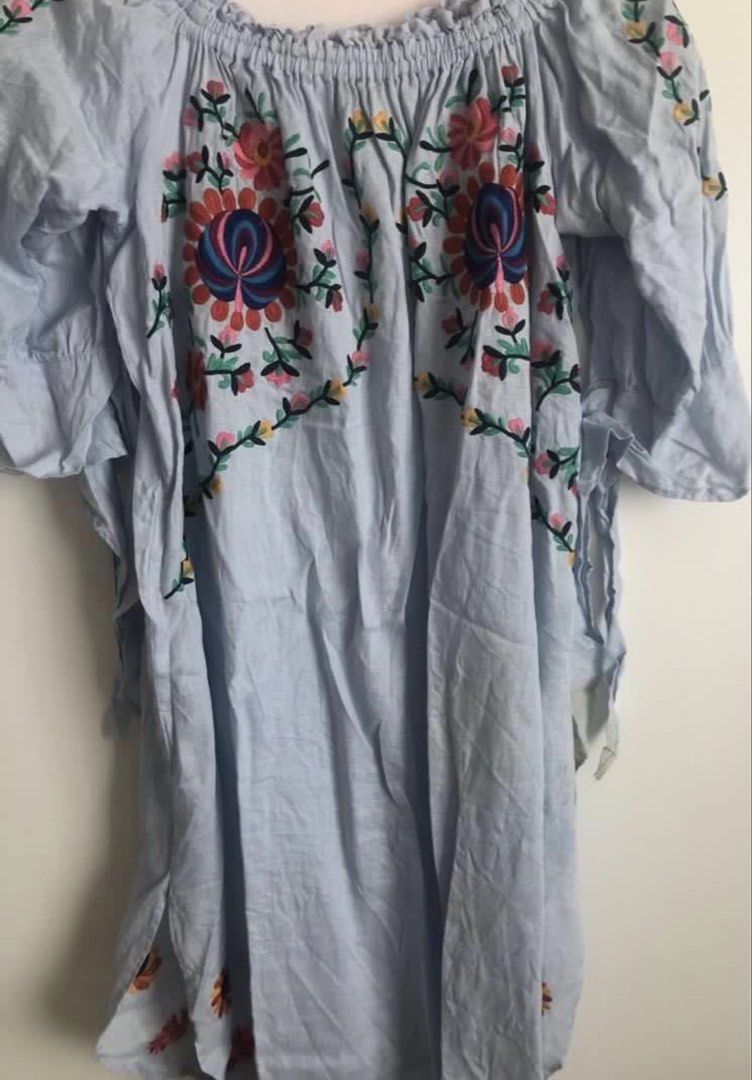 Light blue off-shoulder embroidered floral blouse (Category: Blouses) located in Manila. Submitted by cutielove888 (Listing ID 1470562814, Image 2). Description: - Color: Light blue - Style: Off-shoulder, relaxed fit tunic - Details: Colorful floral embroidery on chest and sleeves, flared half sleeves - Comfort: Soft, breathable fabric perfect for casual wear.