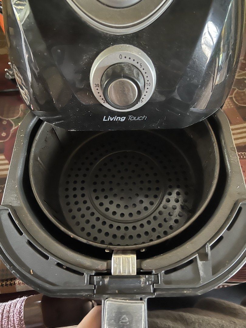 Living Touch Air Fryer Black (Category: Fryers) located in Manila. Submitted by lorrainera64392 (Listing ID 1470604689, Image 2). Description: - Brand: Living Touch - Color: Black - Condition: Working, normal wear on the body - Controls: Dual top knobs for temperature and timer settings - Basket: Removable frying basket with a non-stick perforated tray - Features: Rear exhaust vent with heat warning symbol, standard plug included.