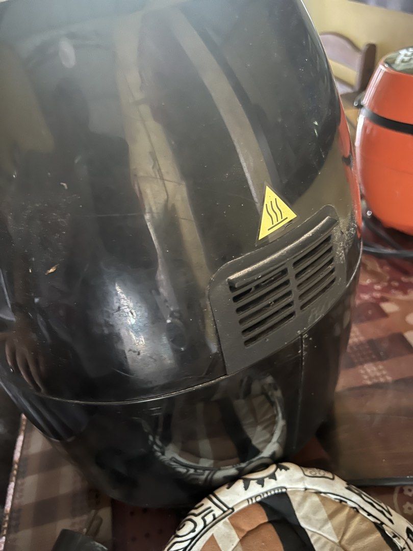 Living Touch Air Fryer Black (Category: Fryers) located in Manila. Submitted by lorrainera64392 (Listing ID 1470604689, Image 3). Description: - Brand: Living Touch - Color: Black - Condition: Working, normal wear on the body - Controls: Dual top knobs for temperature and timer settings - Basket: Removable frying basket with a non-stick perforated tray - Features: Rear exhaust vent with heat warning symbol, standard plug included.