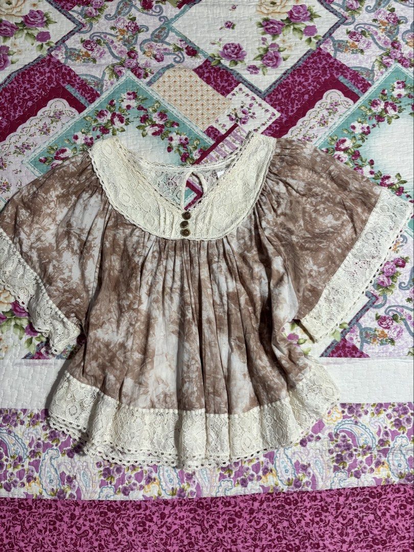Liz Lisa Brown Batwing Top (Category: Blouses) located in Sual. Submitted by cinnamorol_lovar (Listing ID 1470624105, Image 1). Description: - Brand: Liz Lisa (Authentic Japanese Gyaru brand) - Color/Print: Brown tie-dye with cream lace details - Features: Lace collar, cuffs, and hem, pleated bodice, keyhole neckline with gem buttons - Sleeves: Short flared sleeves - Fit: Loose and flowy - Material: Soft and lightweight fabric.