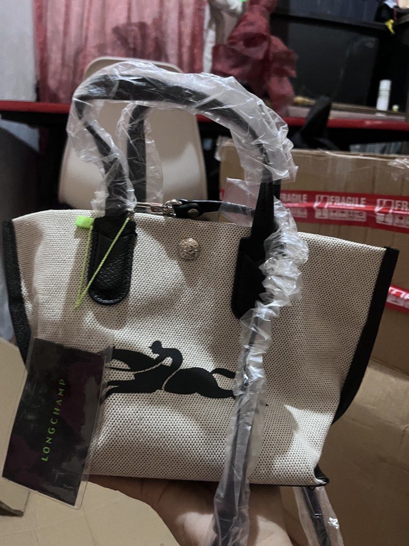 Longchamp Essential Small Handbag Crossbody bag (Category: Tote Bags) located in Manila. Submitted by madecuratedwithlove11 (Listing ID 1470581738, Image 1). Description: - Brand new with tag attached and handles/strap still wrapped in plastic - Longchamp black and white canvas tote bag - Dual top handles and a convenient detachable shoulder strap - Textured fabric body with chic solid black trim - Secure snap button closure - Features Longchamp 