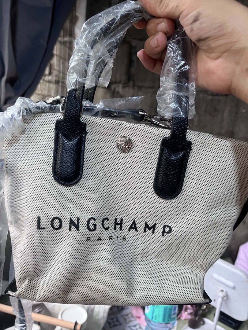 Longchamp Essential Small Handbag Crossbody bag (Category: Tote Bags) located in Manila. Submitted by madecuratedwithlove11 (Listing ID 1470581738, Image 3). Description: - Brand new with tag attached and handles/strap still wrapped in plastic - Longchamp black and white canvas tote bag - Dual top handles and a convenient detachable shoulder strap - Textured fabric body with chic solid black trim - Secure snap button closure - Features Longchamp 
