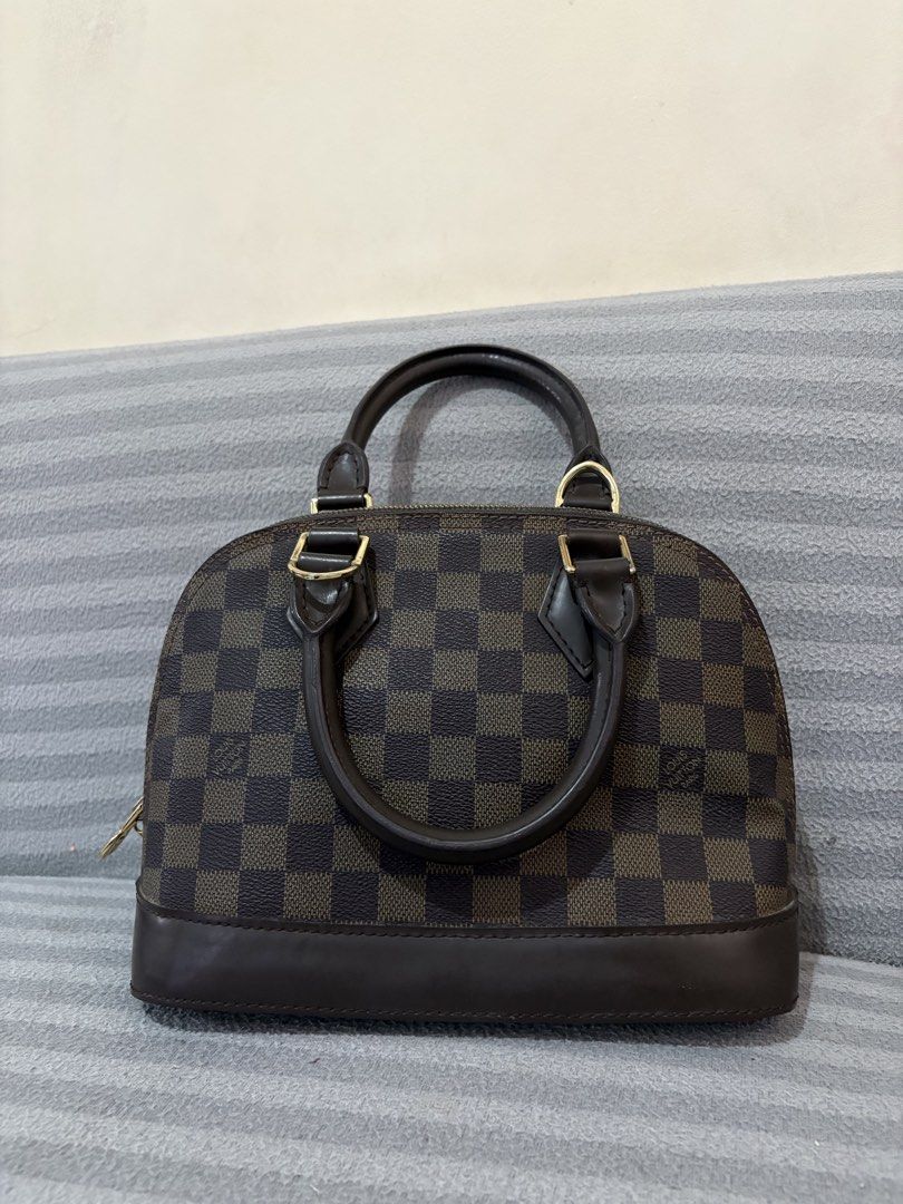 Louis Vuitton Damier Ebene Alma Handbag (Category: Luxury Bags & Wallets) located in Pasig City. Submitted by mau_llamas (Listing ID 1470692373, Image 1). Description: - brown checked coated canvas with dark brown smooth leather trim - Elegant gold-tone hardware and structured dome shape - Dual rolled leather handles for comfortable hand carry - Secure top zip closure to keep your belongings safe - Brown fabric-lined interior complete with a hand