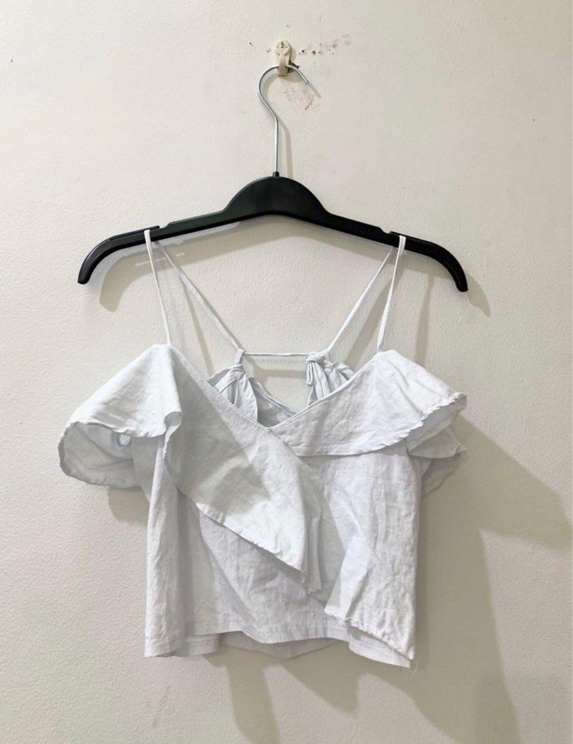 Love Ara White Off-Shoulder Ruffle Strap Crop Top (Category: Sleeveless) located in Quezon City. Submitted by decluttering_alot (Listing ID 1470633573, Image 3). Description: - Style: White cold-shoulder crop top with delicate ruffle layers - Details: Spaghetti straps with thin back connecting detail - Material: Lightweight fabric, ideal for warm weather or outdoor shoots - Condition: Worn once for a brief shoot, practically clean and like new RF