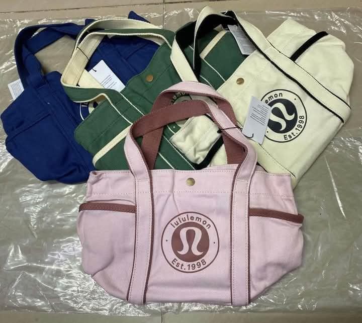 Lululemon Canvas Mini Tote Bag 31x21cm (Category: Tote Bags) located in Del Monte. Submitted by balanijoan70708 (Listing ID 1470670730, Image 2). Description: - Brand new with tags attached - Dimensions: 31x21cm with a 6.5L capacity - Features iconic round logo patch on the front - Secure snap button closure and dual top handles - Practical exterior pockets on both sides plus an interior slip pocket - Available in multiple gorgeous colors: pink, 